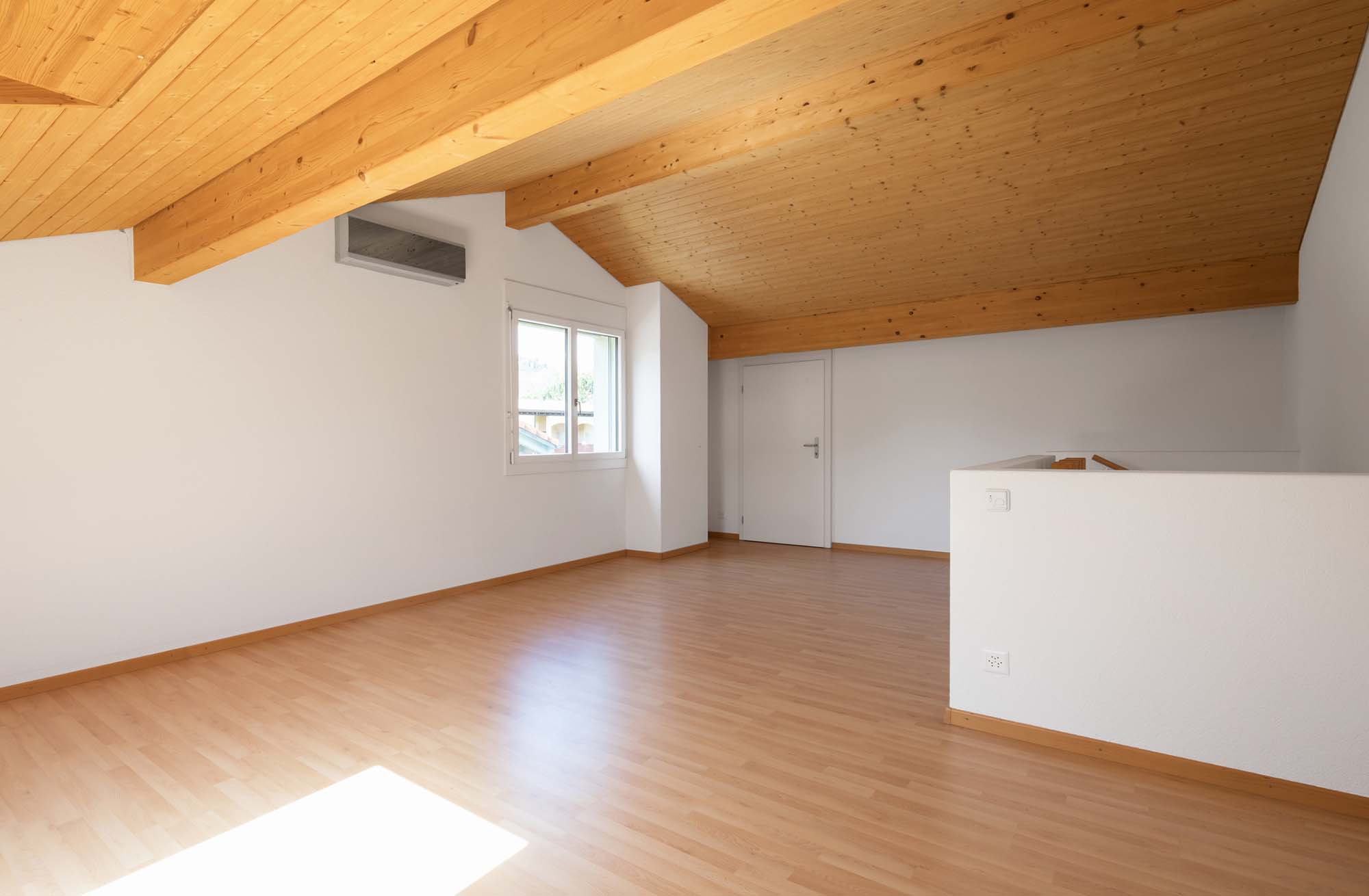 Large attic with wooden floors and exposed beams. White walls, perfect for copy-sace